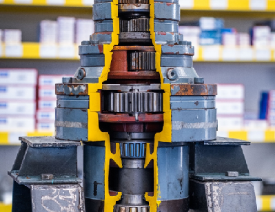 Quarter section of component taken from a wind turbine, showing the gearbox housing, inner spur gears, bearings, and other minor components, sitting vertical on a support stand.