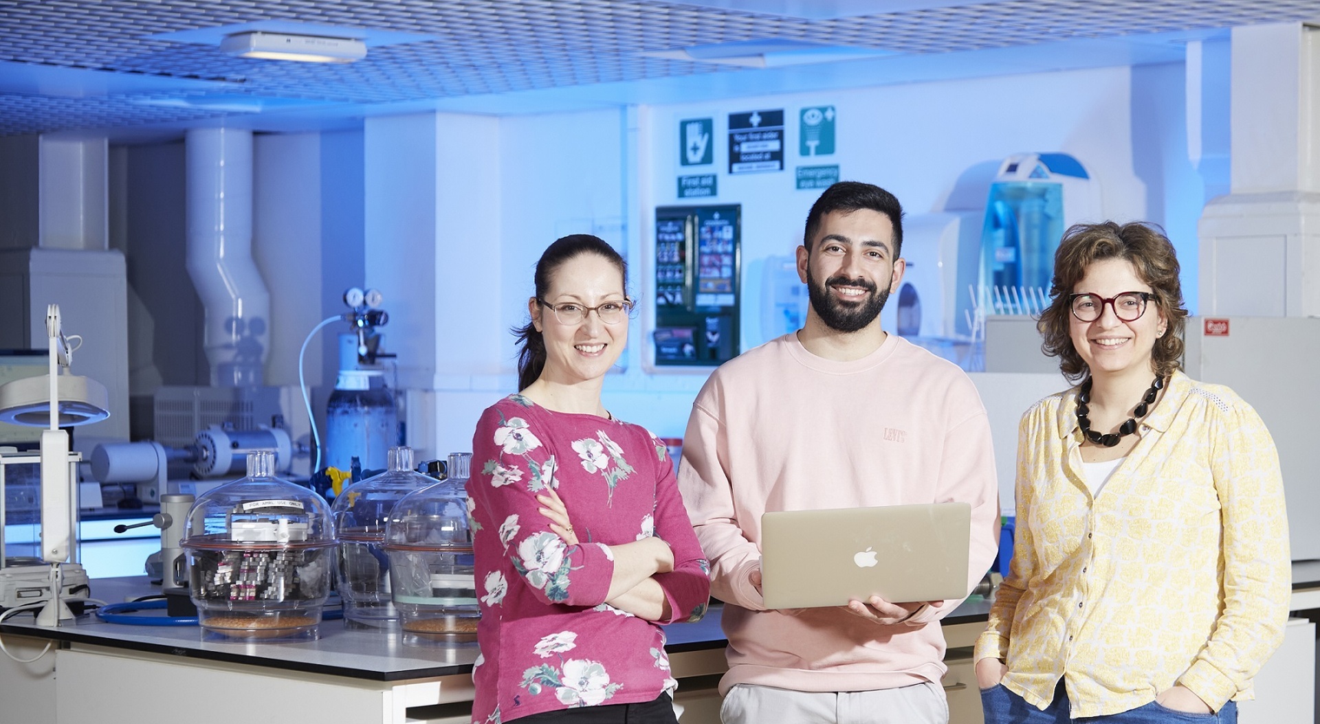 A group of academics in a lab posing with a laptop